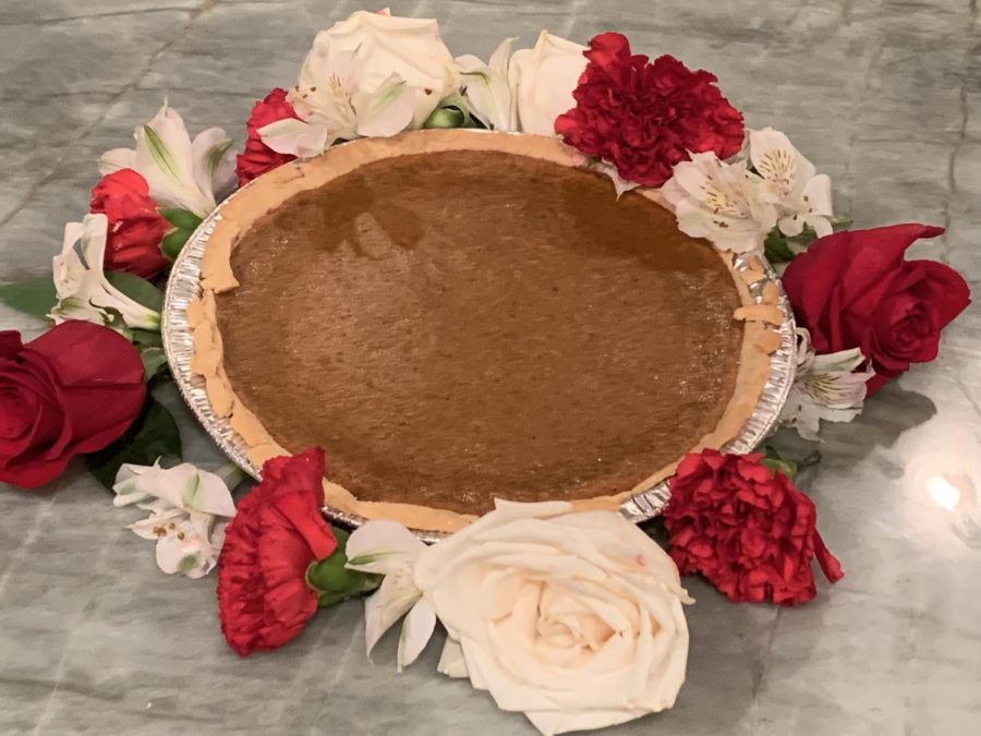 Roses line the tin holding a fresh pumpkin pie. The pie had a lush, buttery crust and a smooth filling.