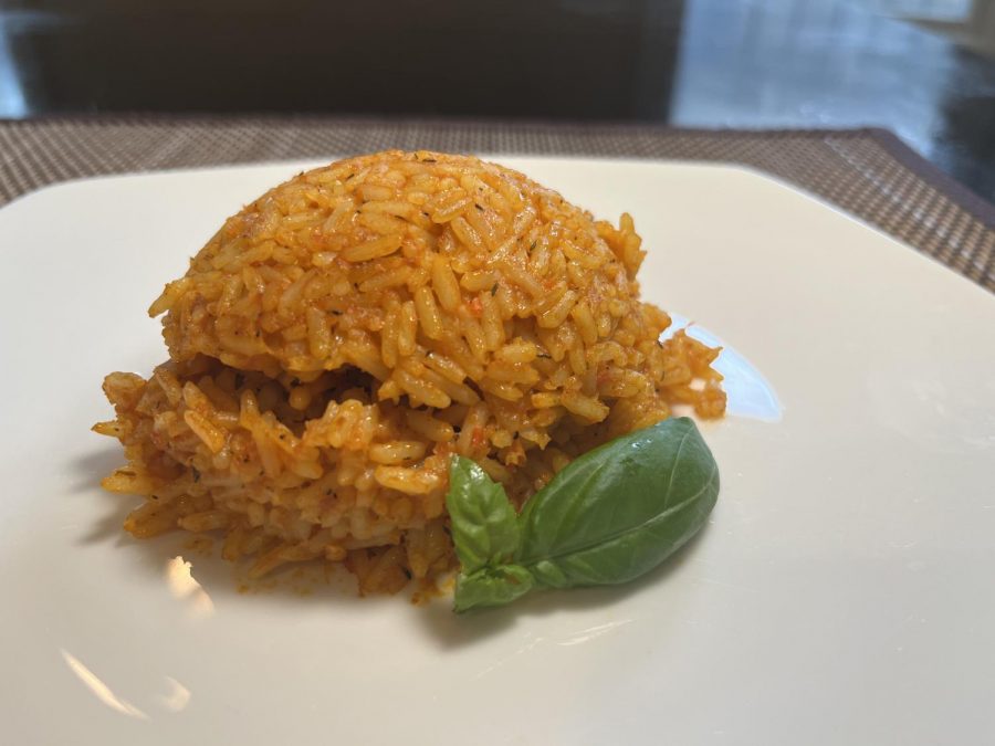The coconut jollof rice when it has been plated and garnished with fresh basil. The coconut mik elevates the flavor of the rice.