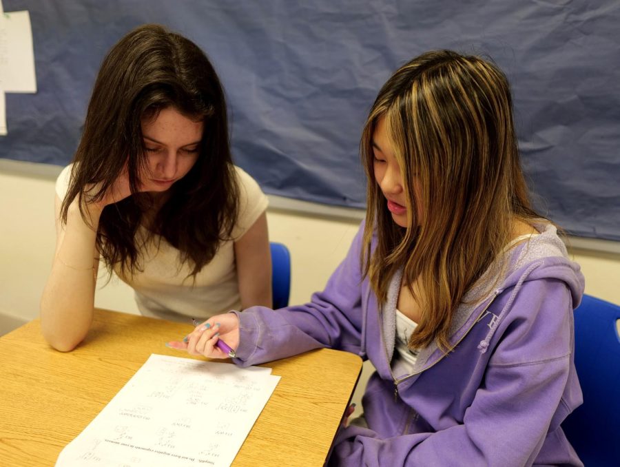 To review for an upcoming pre-calculus test, junior Charlotte Shays listens to junior Katherine Hos explanation of how to work out a math problem. Ho often works with students at Mathnasium where she is a part-time tutor. “I get to see the side of math where people are asking the questions that I never thought of and it builds a more solid understanding of math,” Ho said.