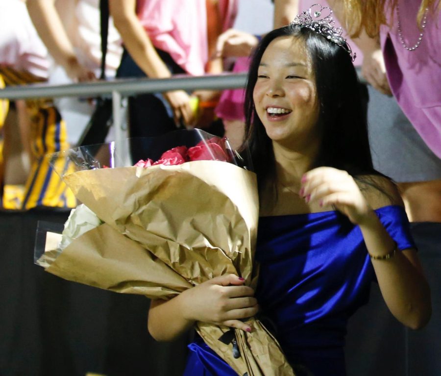 Senior Vivian Jin smiles in front of the student section after being named Homecoming queen. Jin was named queen during the homecoming football game at halftime. The whole night was just really fun and honestly a bit nerve racking as we had to walk on cause there was a lot more people than I had expected she said.