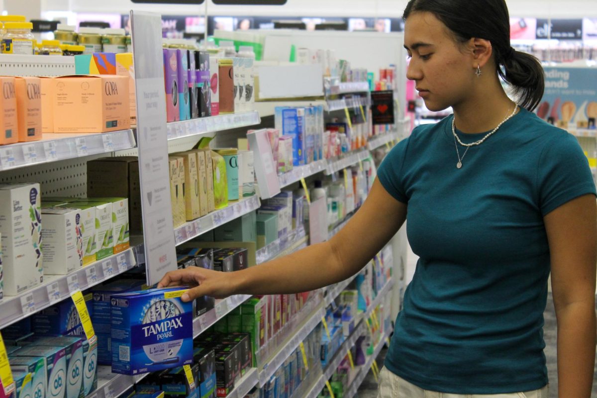 Junior Maxine Jordanoff poses in the menstrual products aisle of a pharmacy.