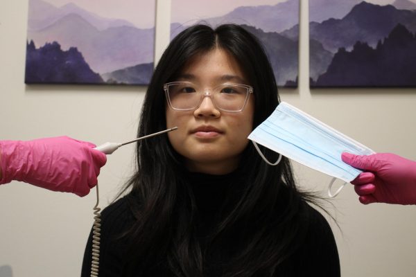 Senior Jenny Deng sits surrounded by medical tools in nurses office. 
