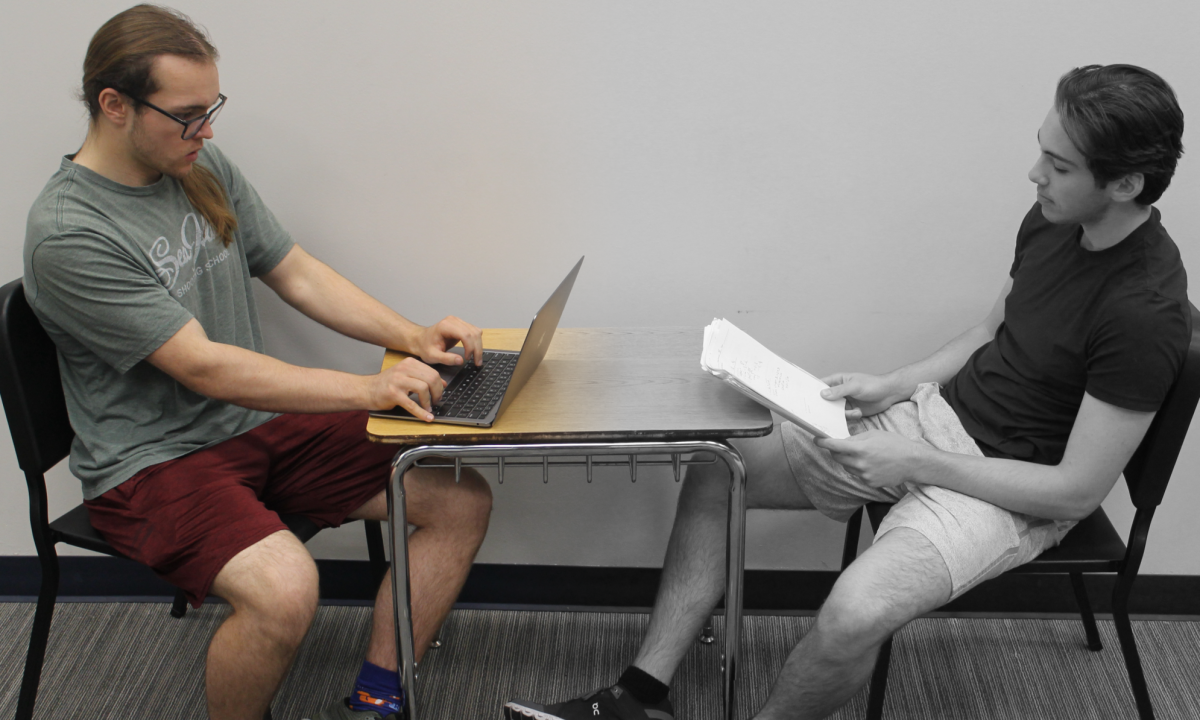 Seniors Gage Swords and Jake Wood pose as test-takers showing the disparity between digital and paper assessments. This year, students nationwide will be taking the PSAT and SAT digitally. 