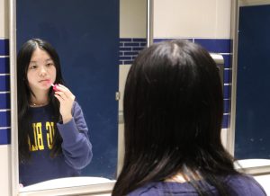 Freshman Emily Luu applies her makeup in the mirror. Recent social media influence has led to a dangerous spike in teenagers irresponsible purchases of skincare and makeup. Senior Priscilla Ngyuen has noticed this trend. “I scroll on TikTok and all I see are young girls doing get-ready with me [videos],”  Ngyuen said. “Even when I’m in shops like Sephora, it’s amazing how many kids I see.