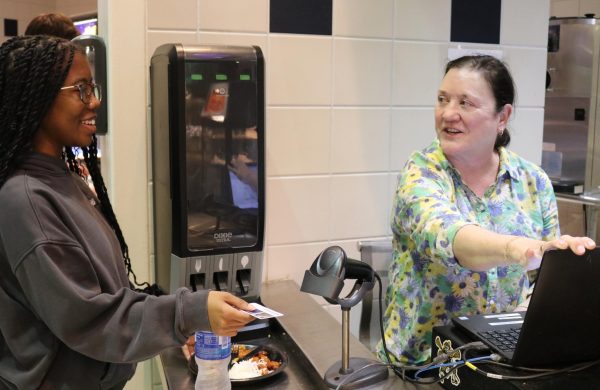 Junior Tia Munyaradzi buys new menu items from the cafeteria lunch line. The cafeteria has changed its menu to contain healthier foods with a wider variety of flavors.